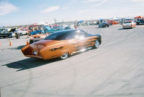 1972 Ford Ranchero - A custom hot rod with flame graphics is seen on a sunny day at an outdoor event with other vehicles present.