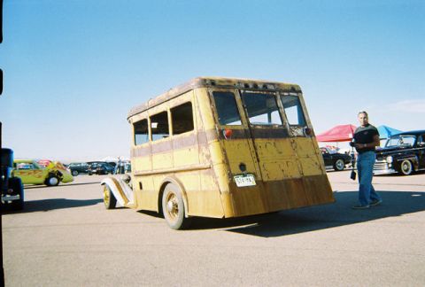 1972 Ford Ranchero - A man stands near a yellow custom bus with a sloped rear, parked outdoors with other vehicles.