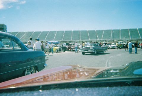 1972 Ford Ranchero - A gathering of vehicles and people in front of stadium bleachers on a sunny day.