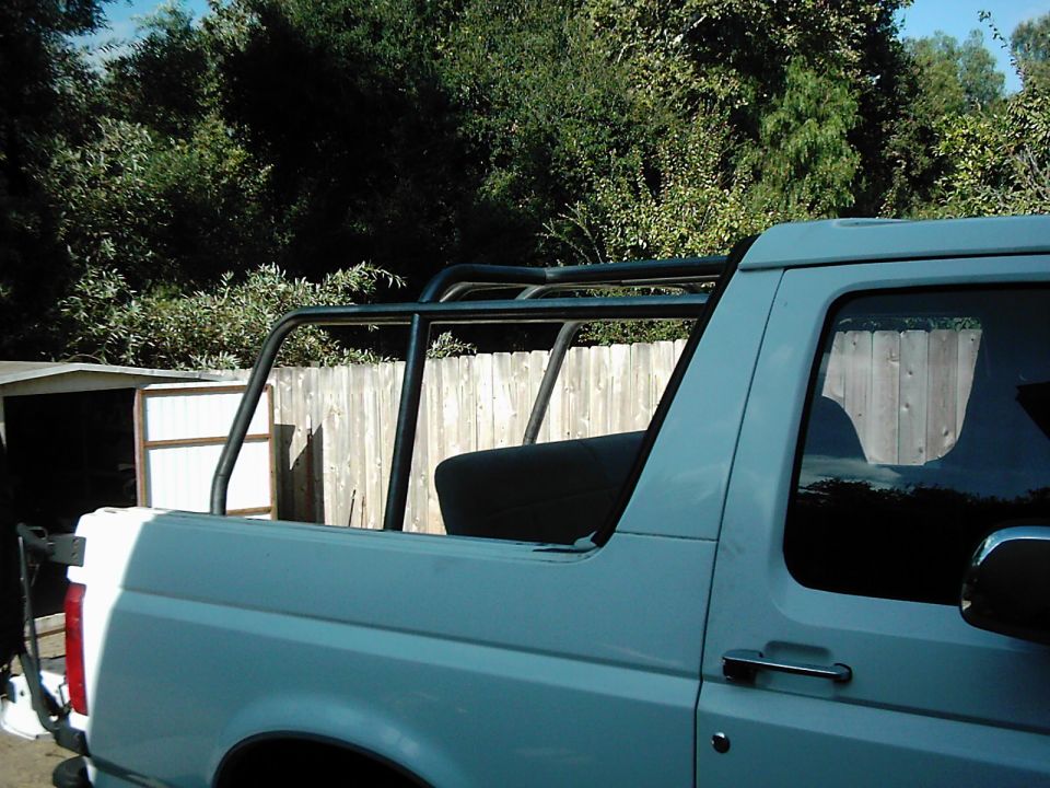White SUV with a black roll cage, seen from the side. The vehicle has a light blue body and a black interior seat visible