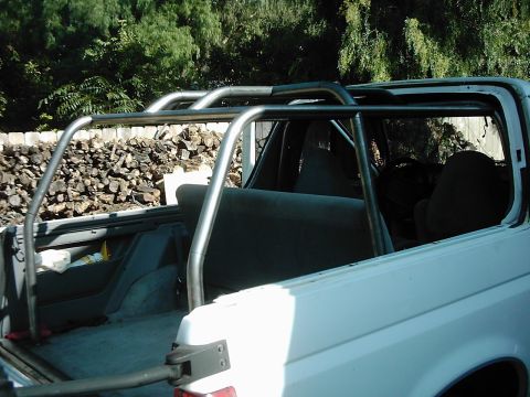 1978 Ford Bronco - Interior view of a white SUV, a prominent roll cage and grey upholstery.