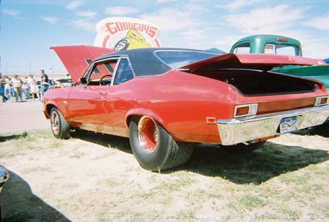 1972 Ford Ranchero - A red muscle car with its hood and trunk open is parked on a grassy lot next to other vehicles.