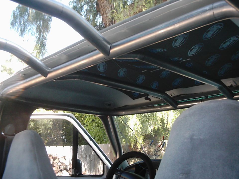 Interior view of an SUV with a roll cage and custom headliner. Steering wheel visible