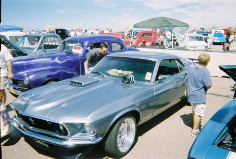 1972 Ford Ranchero - A silver 1969 Ford Mustang coupe is parked at an outdoor car show, with other vehicles and people around.