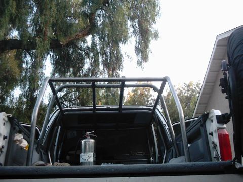 1978 Ford Bronco - The rear of a pickup truck shows a custom roll cage and a fire extinguisher mounted inside the bed.