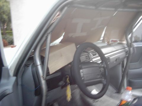 1978 Ford Bronco - The interior of a truck shows a roll cage and cardboard sunshades covering the windshield.