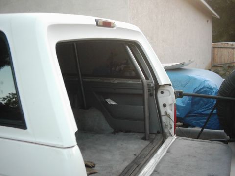 1978 Ford Bronco - The interior of a white SUV is visible, a roll cage and an open tailgate.