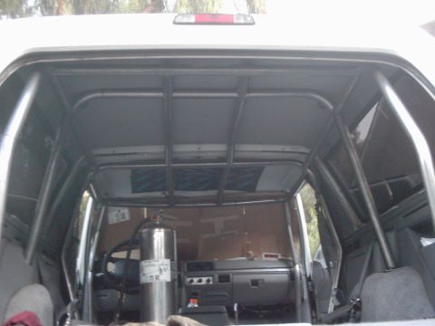 1978 Ford Bronco - The interior of a vehicle is shown with a prominent roll cage and a fire extinguisher. The dashboard and seats are visible.