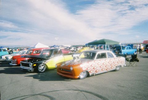 1972 Ford Ranchero - A custom hot rod with flame decals and a prominent engine is displayed alongside other vehicles at an outdoor event.