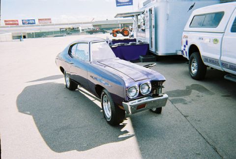 1972 Ford Ranchero - A purple 1972 Chevrolet Chevelle coupe is parked on asphalt, with a white truck and trailer in the background.