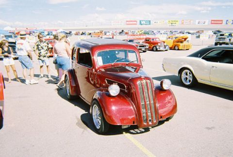 1972 Ford Ranchero - A red sedan with a sunroof is parked at an outdoor event, with other vehicles and spectators in the background.