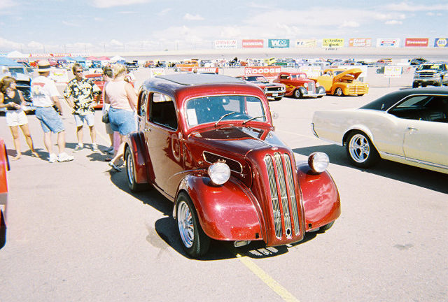 Red sedan with a sunroof parked at a car show