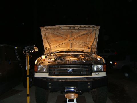 1988 Ford Bronco - Front view of a white Ford F-Series truck with its hood open, revealing the engine bay and a "4x4" badge.