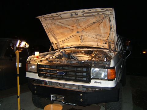 1988 Ford Bronco - Front view of a white 1988 Ford Bronco with its hood open, revealing the engine bay and a winch mounted on the aftermarket bumper.