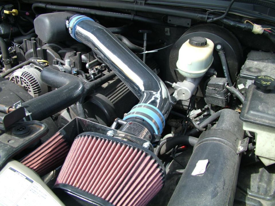 Engine bay with polished aftermarket cold air intake, blue couplers, and red cone air filter