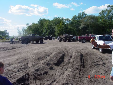 1995 Dodge 1500 - Several modified trucks are gathered in a muddy area, possibly for an off-road event.