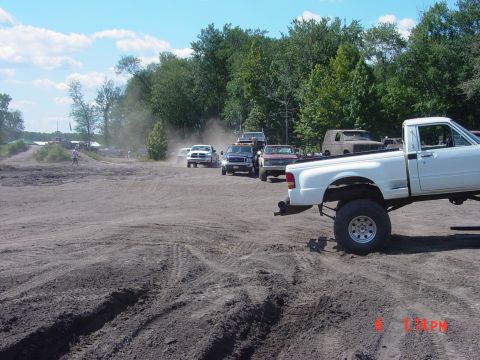 1995 Dodge 1500 - Several trucks are seen in a dusty outdoor area, with a white pickup truck in the foreground.