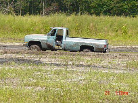 1995 Dodge 1500 - Pickup truck is stuck in a muddy field with tall grass surrounding it.