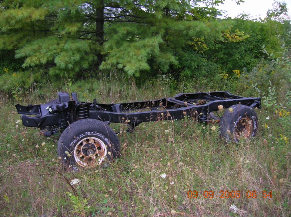 Vehicle chassis with wheels, overgrown with grass and weeds