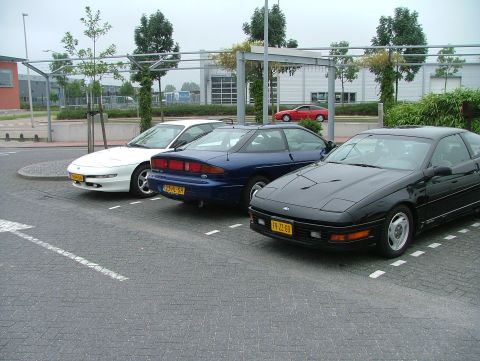 1994 Ford Probe - Three Ford Probes are parked in a lot, with a red car in the background.