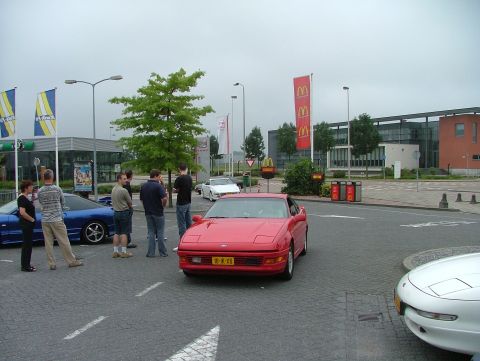 1994 Ford Probe - Several people gather around a red 1994 Ford Probe and a blue Ford Probe in a parking lot.