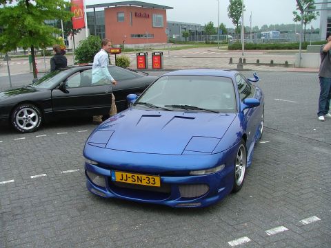 1994 Ford Probe - A blue sports car is parked in a lot next to a black car, with a McDonald's in the background.