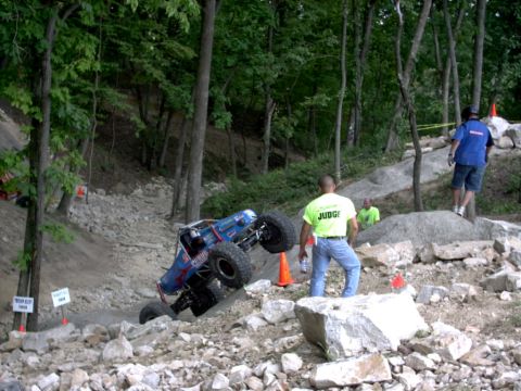 1986 Ford Bronco - A custom-built off-road vehicle navigates a challenging rocky terrain course with officials observing.