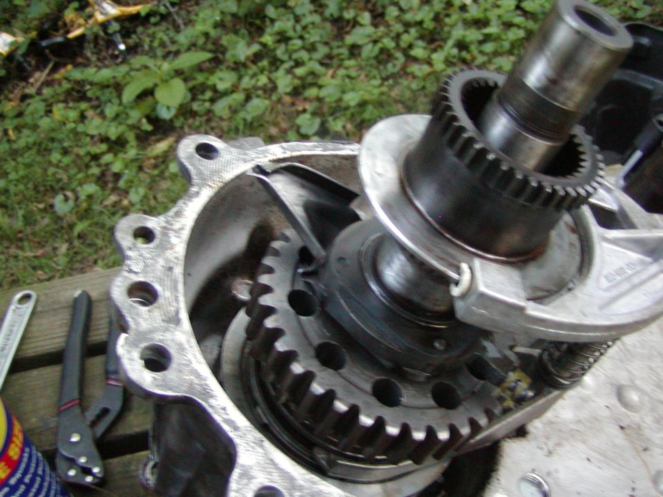 Disassembled Bronco drivetrain component showing output shaft, splined ring, and gears in aluminum housing on a bench