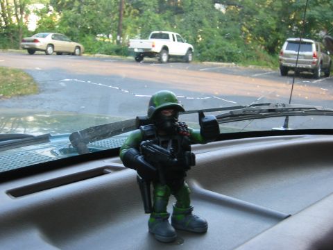 1996 Ford Bronco - An action figure stands on the dashboard of a vehicle, with other cars visible outside.