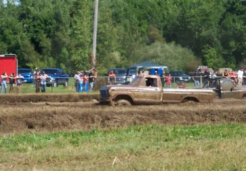 1979 Ford F-150 - A muddy 1977 Ford F-150 navigates a mud pit with spectators watching in the background.