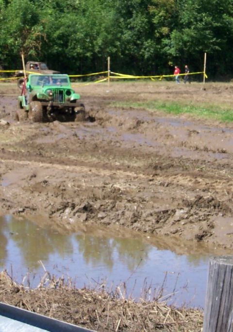 1979 Ford F-150 - Jeep CJ-5 navigates a muddy off-road course, with another vehicle visible in the background.