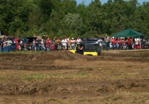 1979 Ford F-150 - An off-road vehicle navigates a muddy track with spectators watching from the sidelines.
