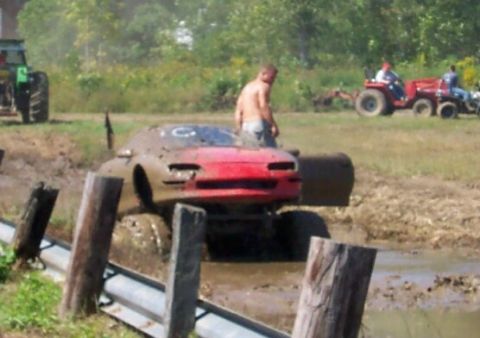 1979 Ford F-150 - Sports car bogged down in mud during an event, with tractors in the background.
