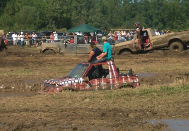 Trucks stuck in mud pit with people watching