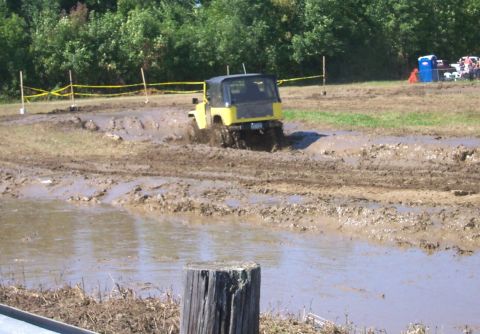 1979 Ford F-150 - A yellow off-road vehicle navigates a challenging mud course during an event.