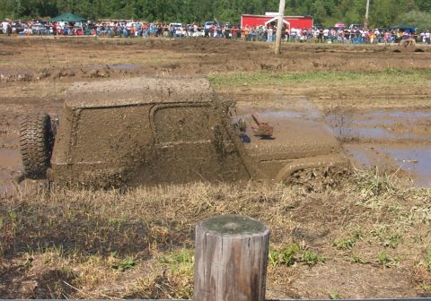 1979 Ford F-150 - A heavily mud-covered vehicle is stuck in a muddy field with spectators in the background.