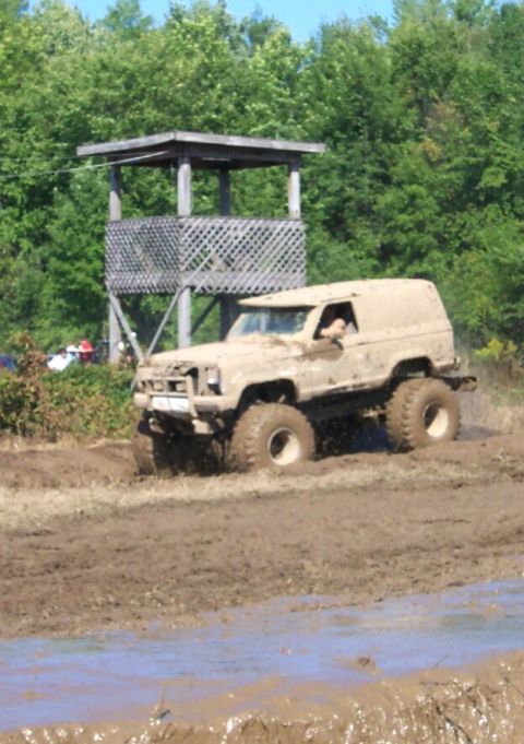 1979 Ford F-150 - This heavily modified off-road vehicle is shown in action during a mud bog event, with a wooden observation tower in the background.
