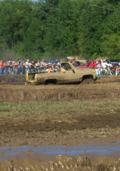 1979 Ford F-150 - Mud bogging event with a yellow pickup truck partially submerged in mud.