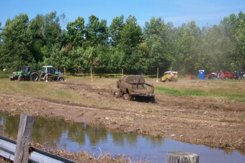 1979 Ford F-150 - A truck is stuck in the mud during an off-road event with other vehicles and spectators present.
