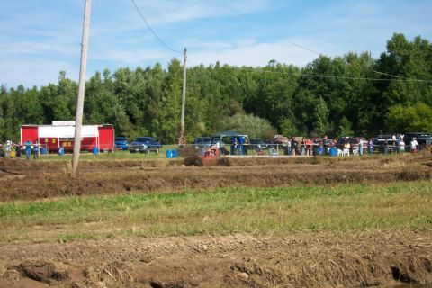 1979 Ford F-150 - A muddy field with several trucks and people gathered, suggesting an outdoor event or competition.