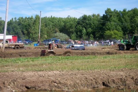 1979 Ford F-150 - Vehicles compete in a mud bogging event, kicking up mud and water.