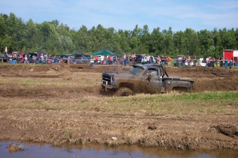 1979 Ford F-150 - A truck is stuck in the mud during an event with a crowd watching.