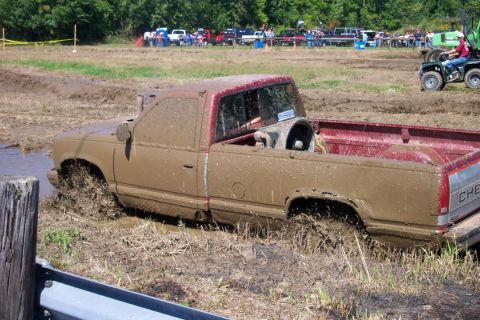 1979 Ford F-150 - Pickup truck stuck in mud during an event. Multiple vehicles and spectators are visible.