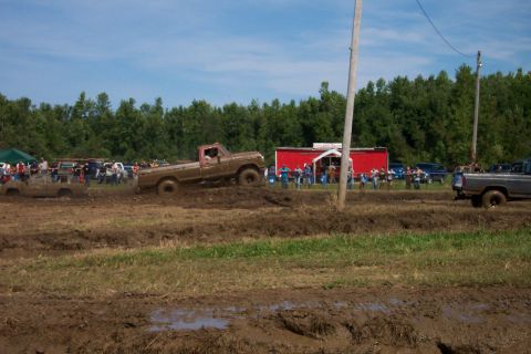 1979 Ford F-150 - A 1979 Ford F-150 navigates a challenging mud course with spectators in the background.