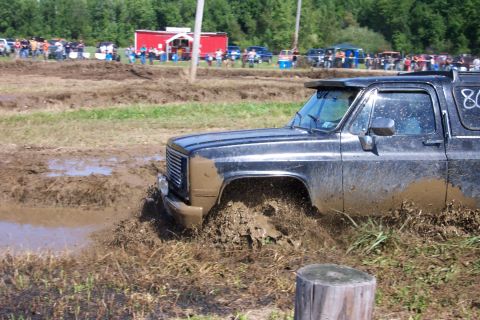 1979 Ford F-150 - A black SUV navigates a muddy obstacle course, with the number "80" visible on its side.