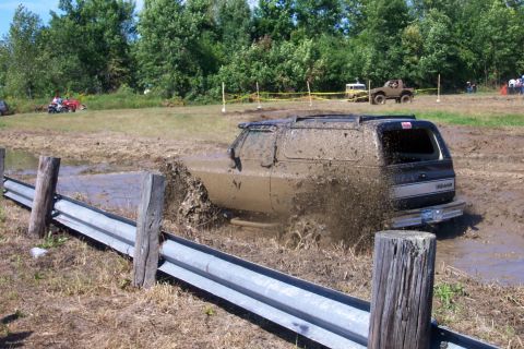1979 Ford F-150 - Off-road vehicle navigates a challenging mud bog, creating a large splash.