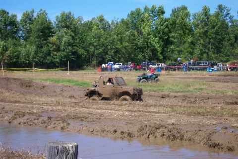 1979 Ford F-150 - An off-road vehicle is stuck in the mud during an event, with an ATV and spectators visible.