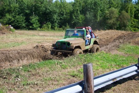 1979 Ford F-150 - A Jeep CJ-5 navigates a muddy obstacle course, kicking up dirt and water.