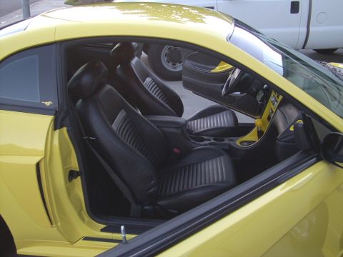 2002 Ford Mustang - Interior view of a yellow 2002 Ford Mustang, showing black seats and dashboard details.