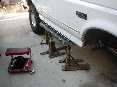 1978 Ford Bronco - White Ford Bronco on jack stands, undergoing modifications with new side steps installed.